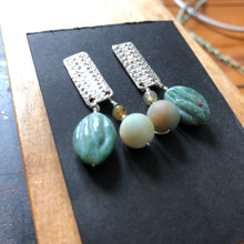 Load image into Gallery viewer, Textured Sterling Silver Rectangle Post Earrings with Carved Green Stone  side angle on black card set on wood back ground
