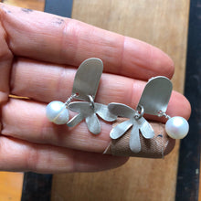 Load image into Gallery viewer, Door and Flower Sterling Silver Post Earrings with White Pearl being held in a hand above wood block