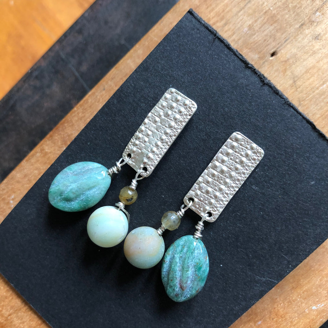 Textured Sterling Silver Rectangle Post Earrings with Carved Green Stone . photo taken from above. black card set on wood back ground